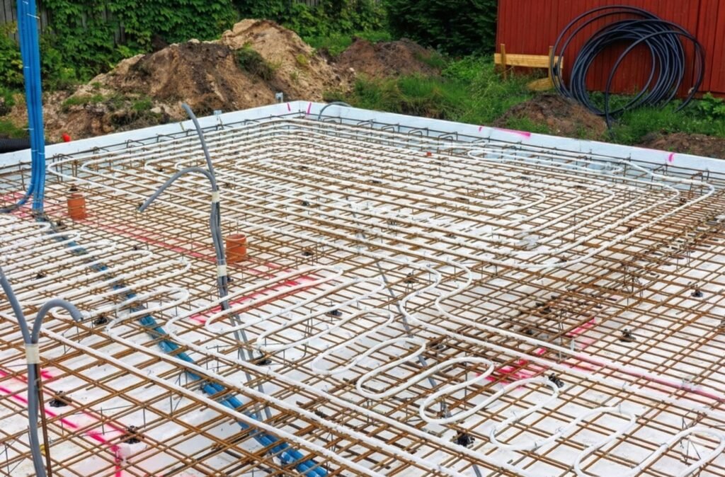 Construction photo showing the PEX tubing grid looped over rebar before the concrete is poured